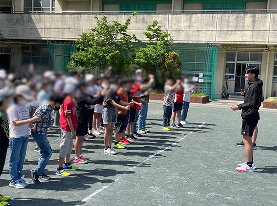 小学生でも分かりやすいよう<br>笑顔で丁寧に教える米田選手(画像)